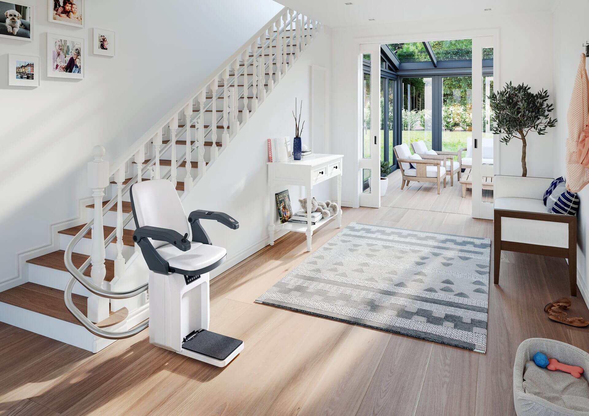 Moderne Treppenlift-Lösung in einem hellen Eingangsbereich mit Holztreppe, die Barrierefreiheit und Komfort bietet. Der Treppenlift ist in einem stilvollen, minimalistisch eingerichteten Raum platziert, der auch einen Blick auf den Garten durch große Fenster ermöglicht.